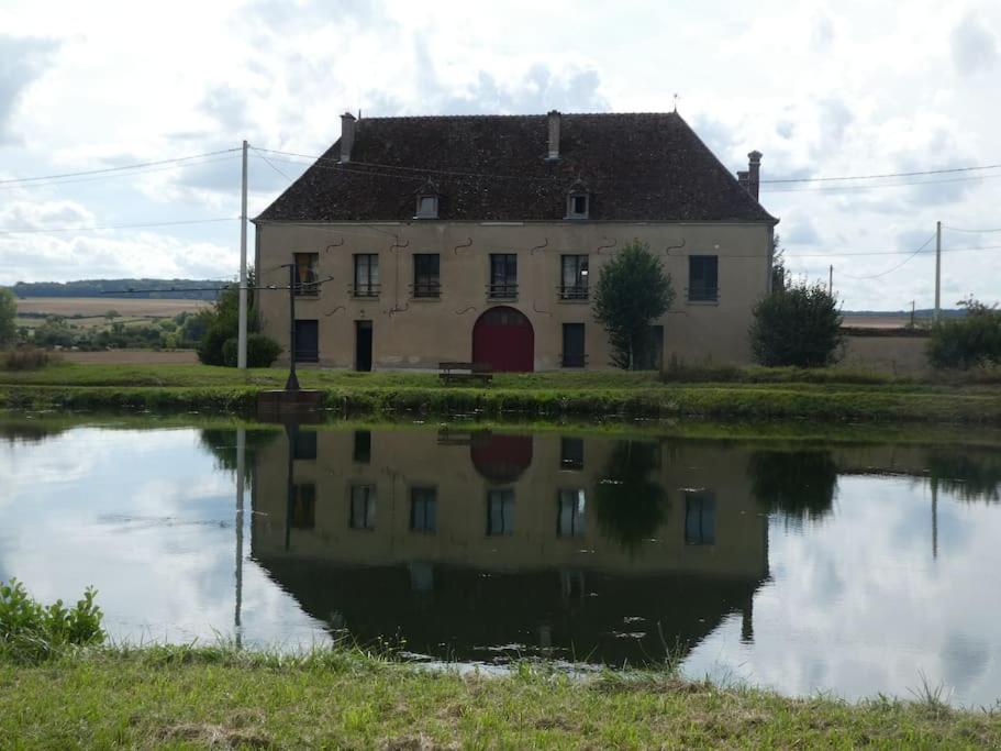 ein altes Haus mit seinem Spiegelbild in einem Wasserkörper in der Unterkunft Le gîte de l'écluse in Marolles-sous-Lignières