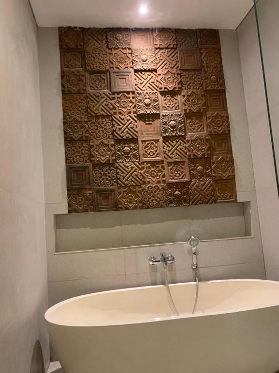 La salle de bains est pourvue d'une baignoire et d'un mur en carrelage. dans l'établissement The Hita Apartement, à Seminyak