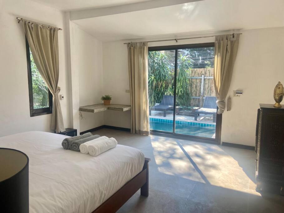 a bedroom with a bed and a view of a pool at Bamboo Villa in Ko Tao