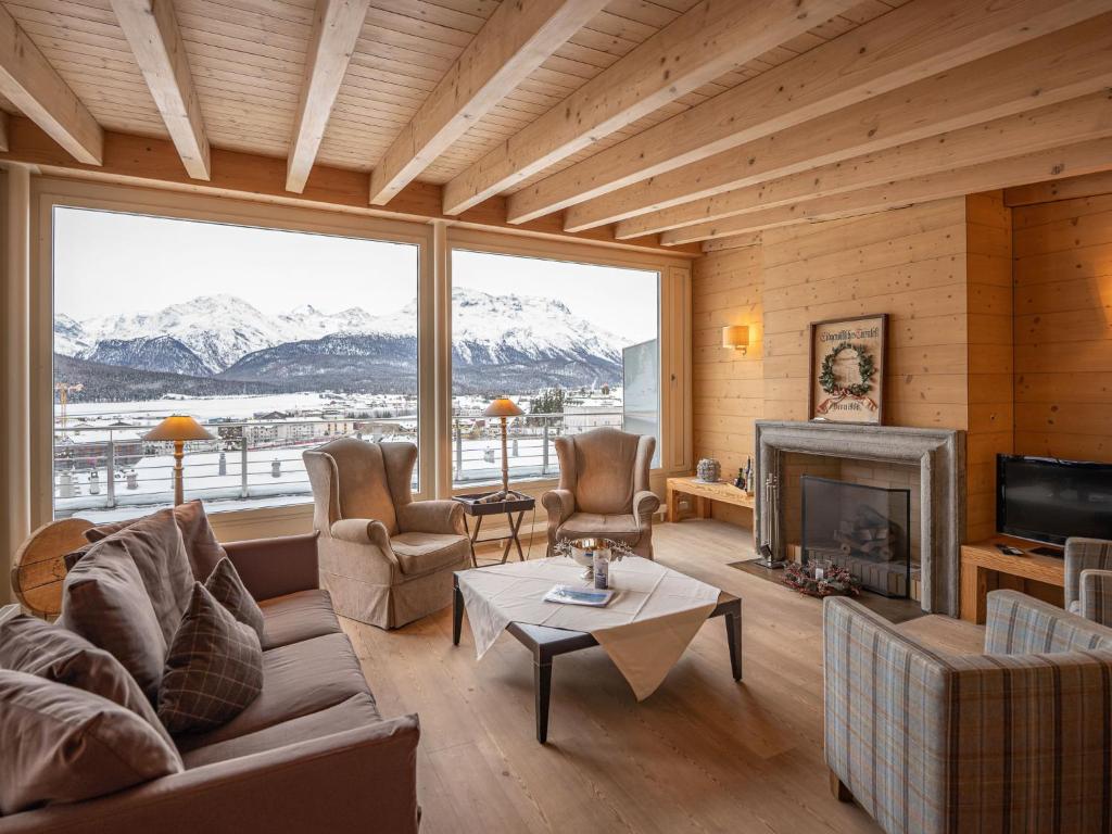 ein Wohnzimmer mit einem Kamin und einem großen Fenster in der Unterkunft Apartment Chesa Crusch 7 by Interhome in Samedan