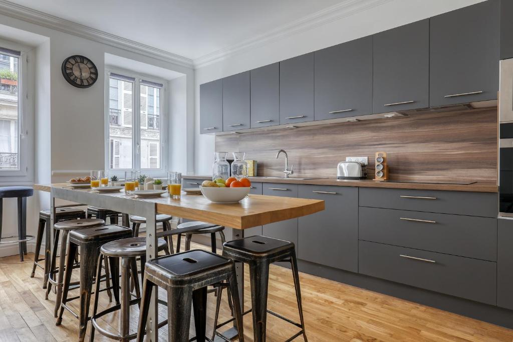 kuchnia ze stołem i stołkami barowymi w obiekcie Superb Large and New 4bds Flat - Heart of Paris 10 w Paryżu