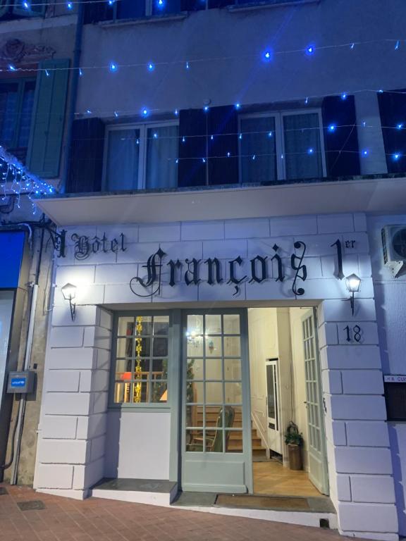 un magasin avec un panneau sur le côté d'un bâtiment dans l'établissement Hotel François 1Er, à Manosque