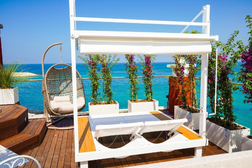 un letto su una terrazza con vista sull'oceano sullo sfondo di Apulia Charming Suites - Casa Rossa Suite Perla e Suite Corallo a Savelletri