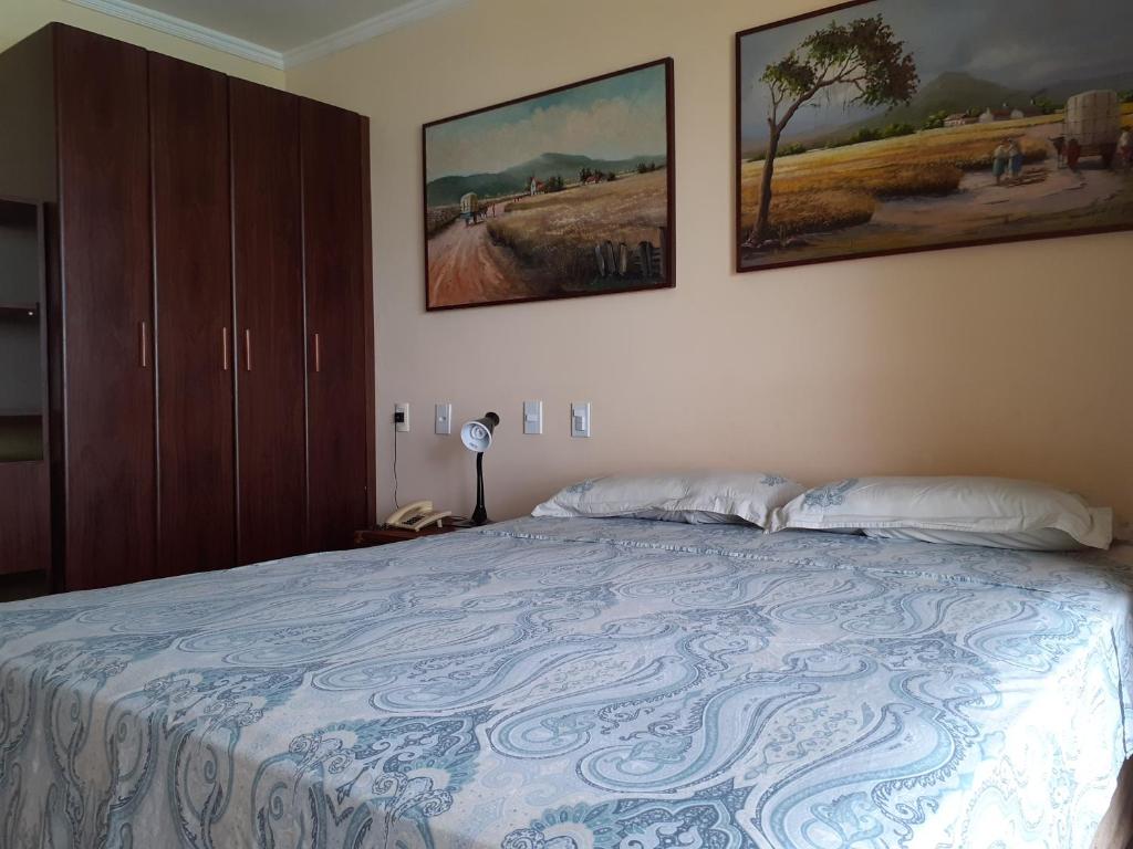 Un dormitorio con una cama con dos cuadros en la pared. en Happy 313 apartamento Frente mar, en Natal