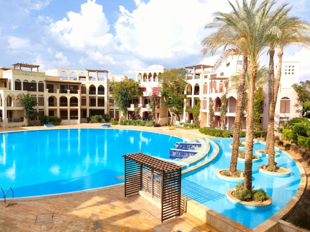 one bedroom apartments aqaba on 2 swimming pool Tala bay في العقبة: مسبح كبير بالنخيل والمباني