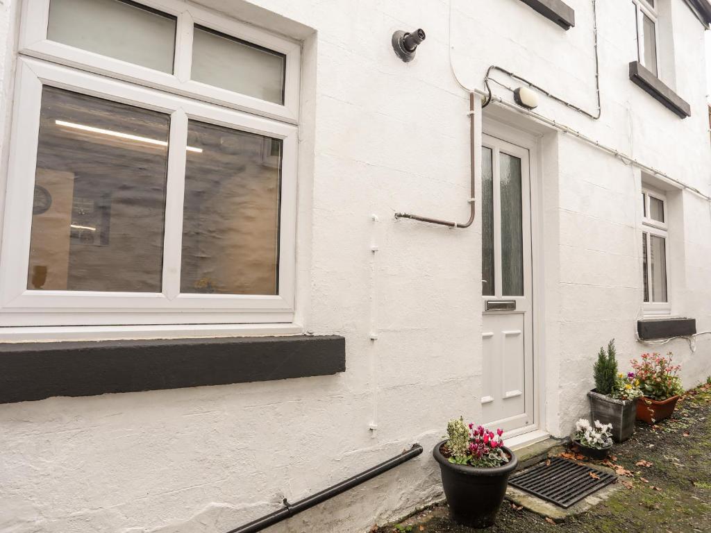 a white house with a window and potted plants at Llys Mair in Bala