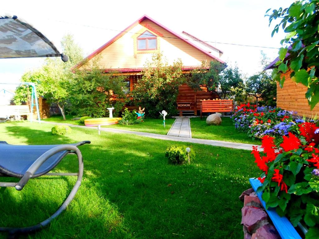 a yard with a house and some flowers and a bench at agrousad'ba Okolitsa in Shchibri