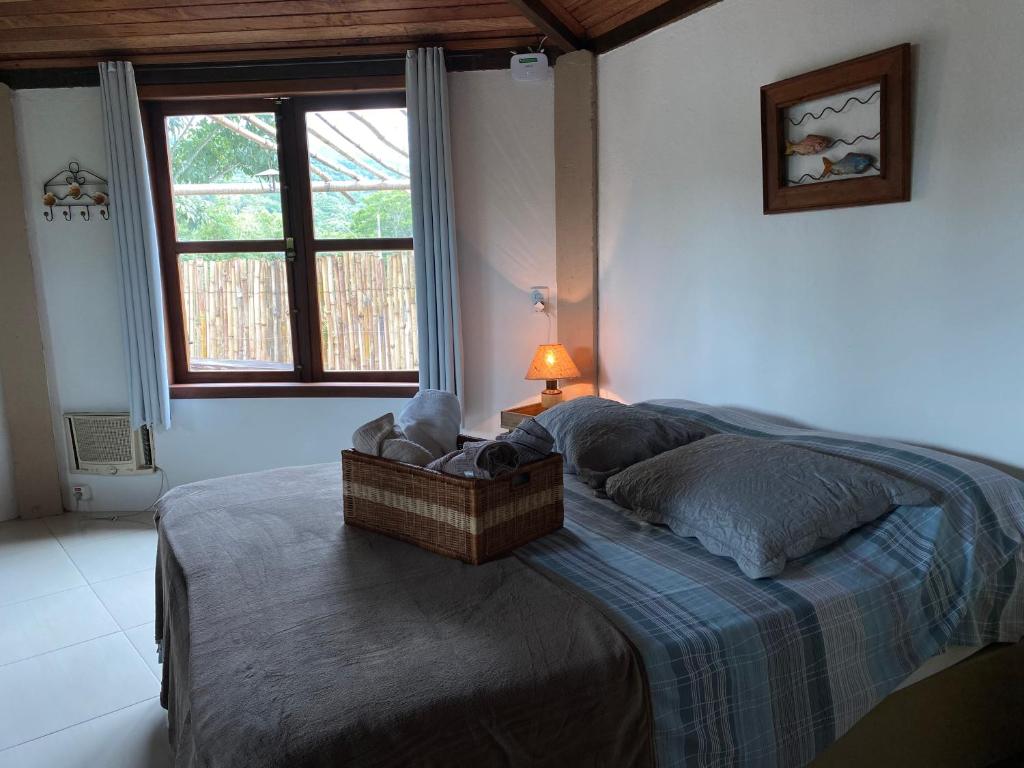 Un dormitorio con una cama con una manta azul y una ventana. en Casinha de Hóspedes, en Pedro Leopoldo
