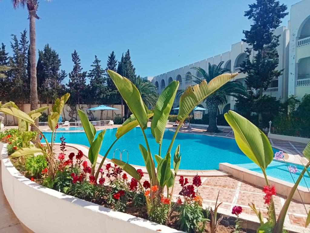 - une piscine dans un complexe avec des plantes et des fleurs dans l'établissement Residence Royal - Deluxe, à Hammamet Sud