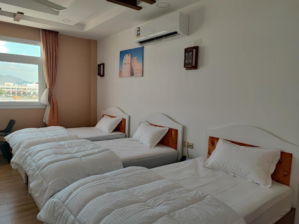 three beds in a room with a window at Dar Al Salaam Hospitality House in Nizwa