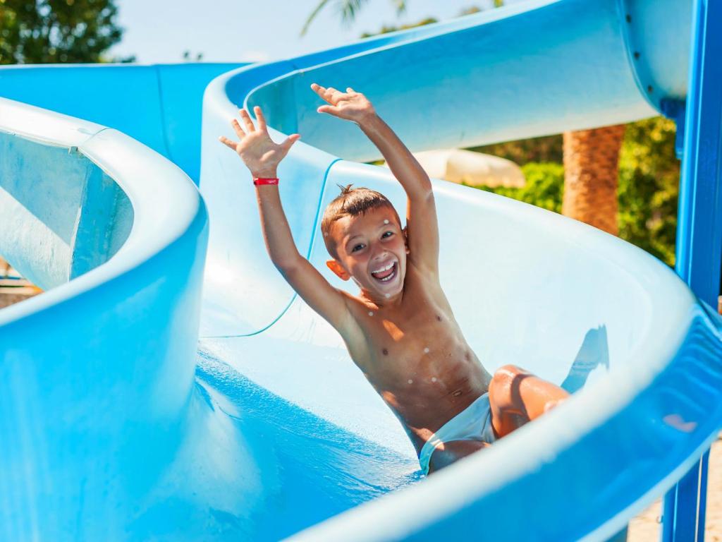 a young man on a water slide in a pool at Calaserena Resort in Geremèas