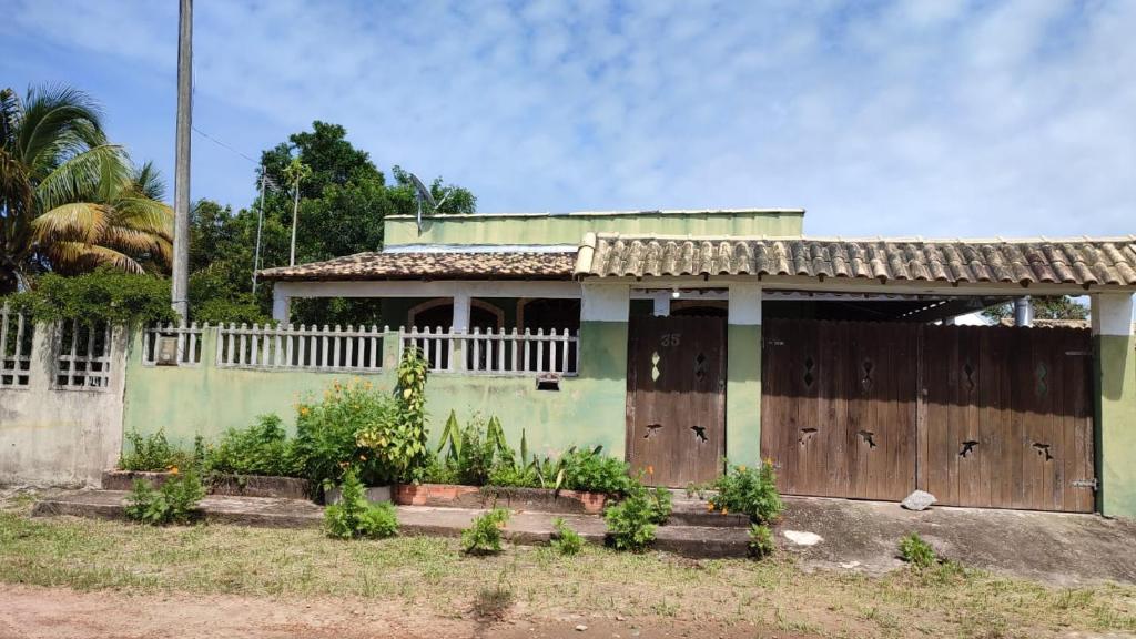 ein Haus mit zwei Holztüren und einem Zaun in der Unterkunft Recanto dos Jardim's Arraial do Cabo in Arraial do Cabo