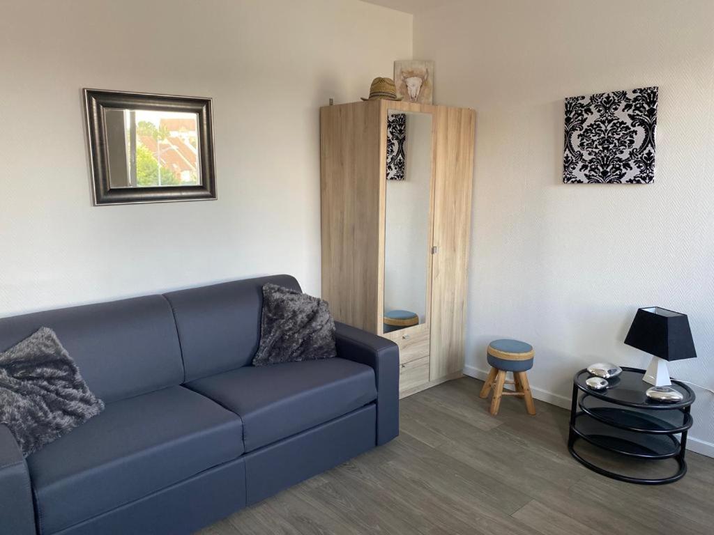 ein Wohnzimmer mit einem blauen Sofa und einem Tisch in der Unterkunft jolie studio in Arras