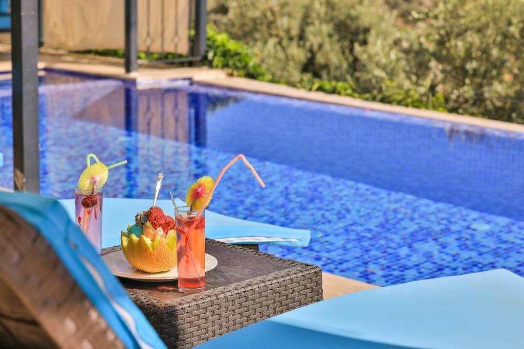 a table with drinks and fruit on it next to a swimming pool at Villa Çalıkuşu Kalkan in Kaş