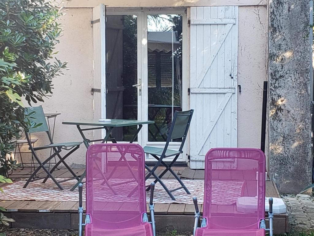 2 sillas rosas y una mesa en el patio en Studio entre Nimes et Uzes, en Lédenon