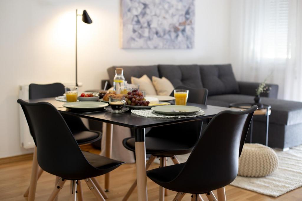 a dining room table with chairs and a table with fruit on it at Apartman Čakovec in Čakovec