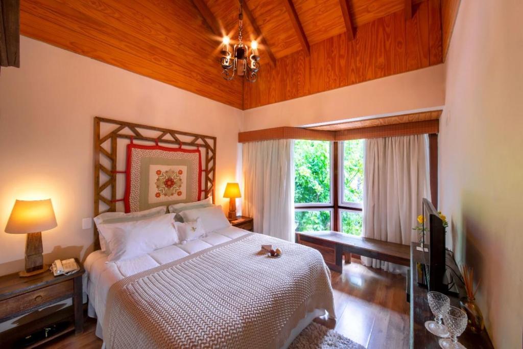 a bedroom with a white bed and a window at Petit Casa da Montanha in Gramado