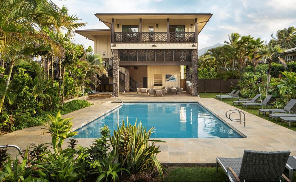 a house with a swimming pool in front of a house at Hanalei Colony Resort in Hanalei