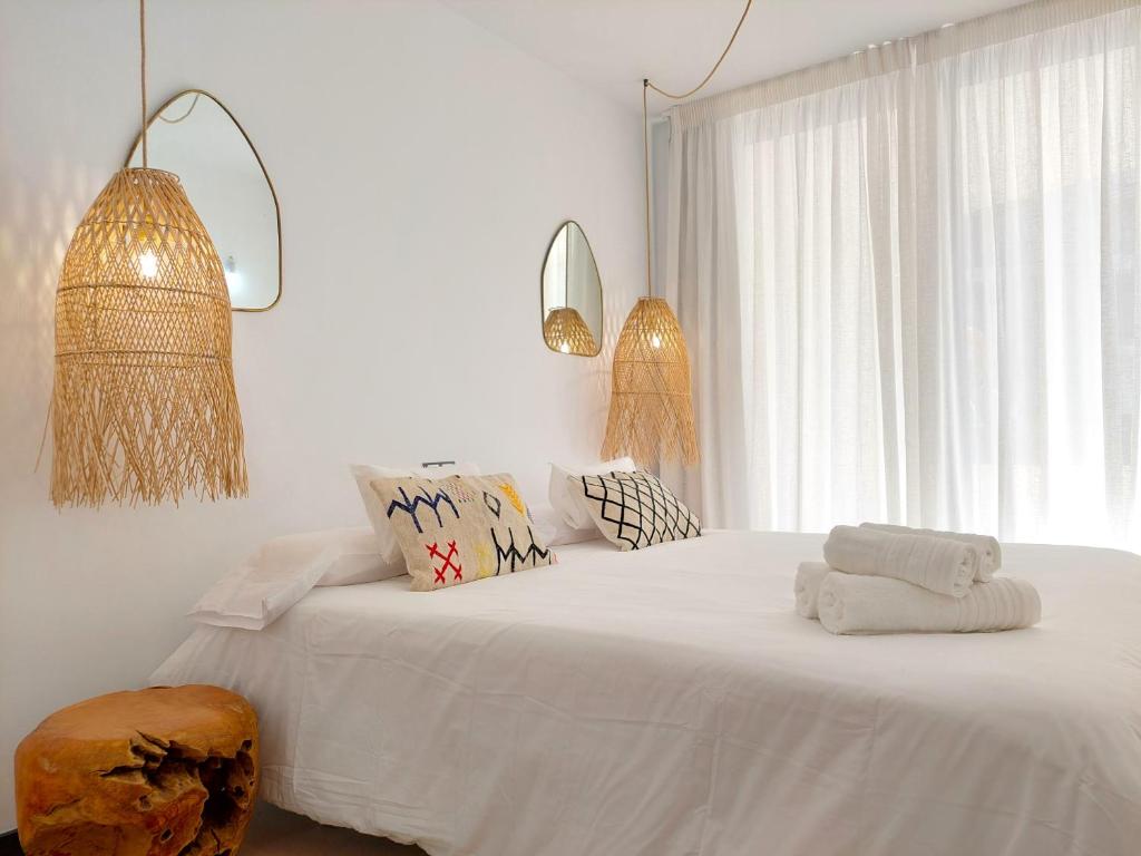 a bedroom with a bed with white sheets and a window at Beach Suite Cotillo by Sea You There Fuerteventura in El Cotillo