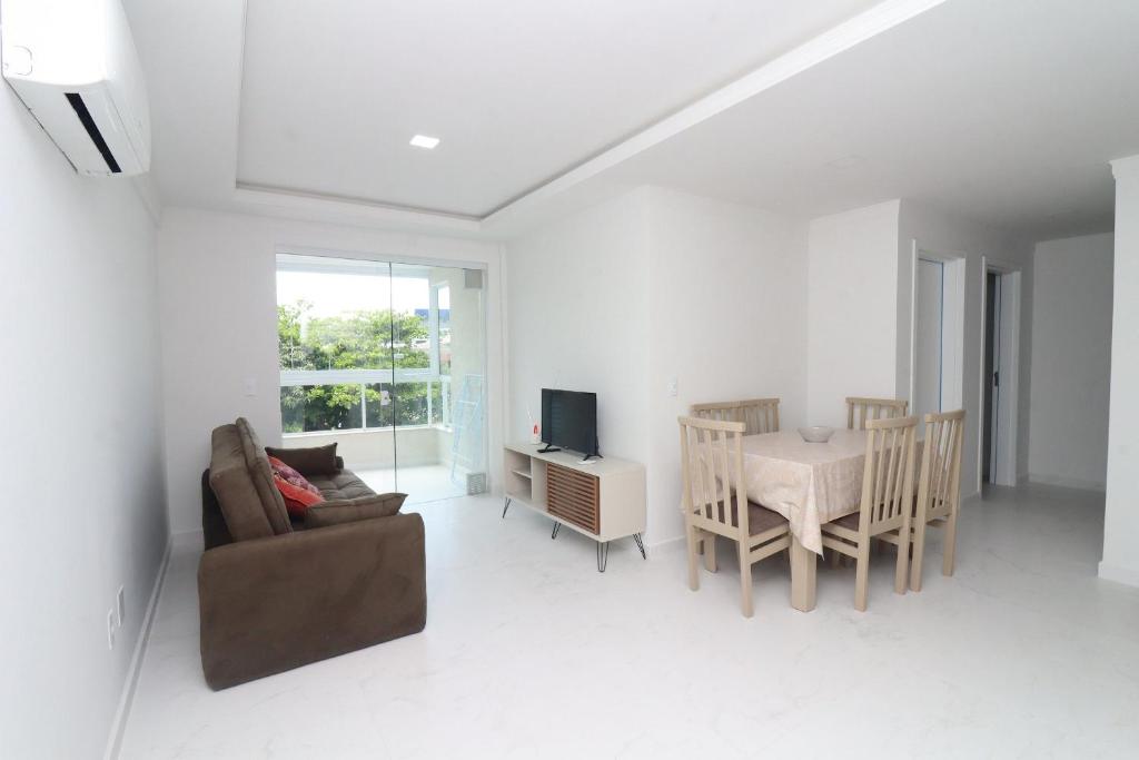 sala de estar con sofá, mesa y silla en Localização privilegiada para 7 pessoas - NY02H, en Florianópolis