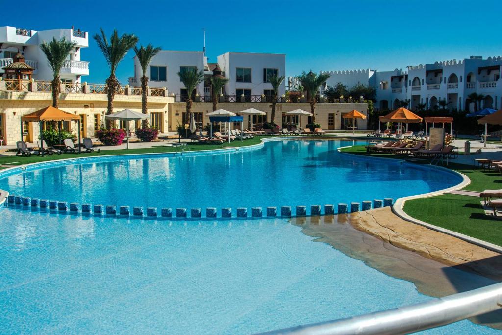 Palma Di Sharm Hollywood Resort في شرم الشيخ: مسبح كبير في منتجع به طاولات وكراسي