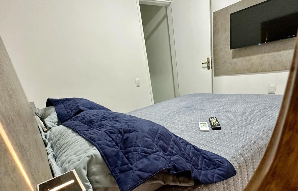 - un lit avec une couette bleue et une télécommande dans l'établissement Fortal Flat, à Fortaleza