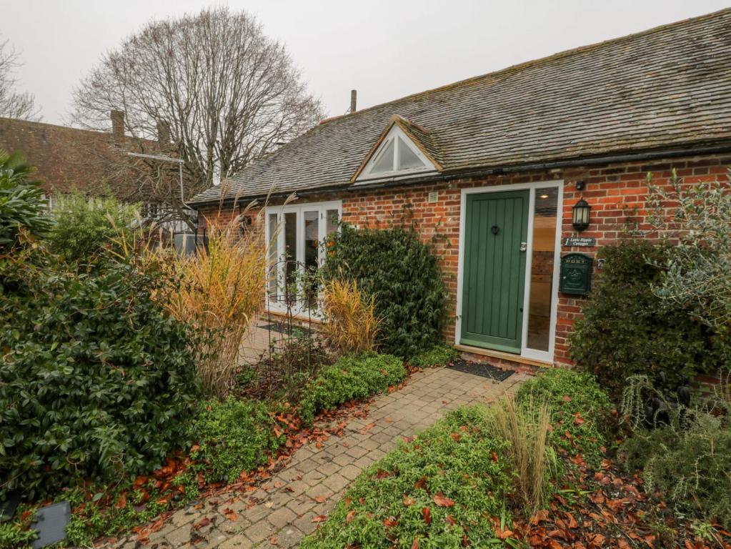 a brick house with a green door in a yard at 1 Little Ripple Cottages in Canterbury