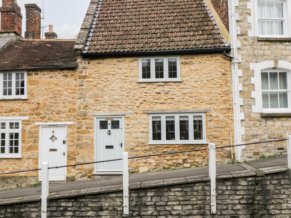 een stenen huis met witte deuren en een stenen muur bij Foxden in Sherborne