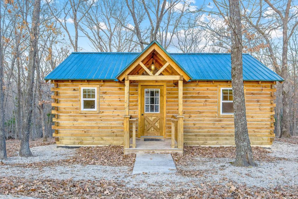 a wooden cabin with a blue roof in the woods at The Eldon Cabin Experience in Eldon