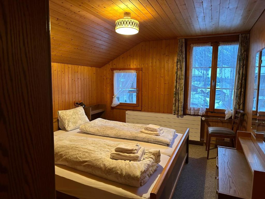 een slaapkamer met 2 bedden in een houten kamer bij Hotel Bären Lodge in Kiental
