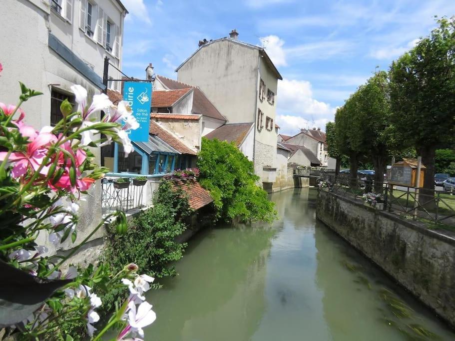 a river in a city with buildings and flowers at La Marisa, studio cosy 10min Disney. in Crecy la Chapelle