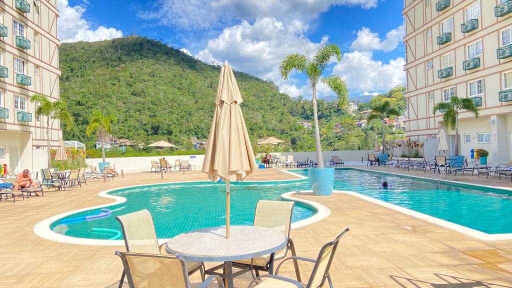 - une table avec un parasol et des chaises à côté de la piscine dans l'établissement Estúdios Em Itaipava - Granja Brasil - Conforto e Lazer, à Itaipava