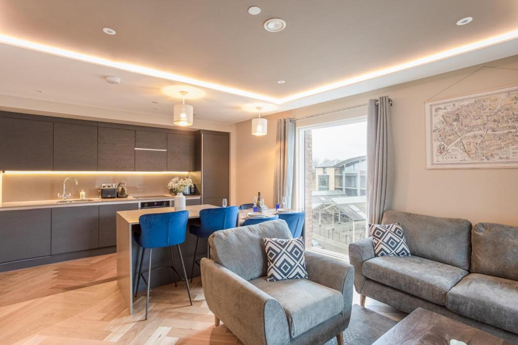 a kitchen and living room with blue chairs and a couch at Luxury 2 bedroom apartment with free parking in the heart of York in York