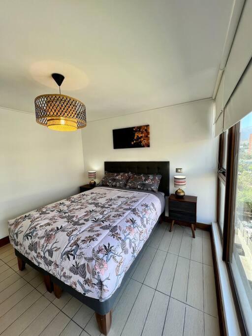um quarto com uma cama e uma grande janela em Lindo y equipado depto de 1d/1b en Metro Manquehue em Santiago