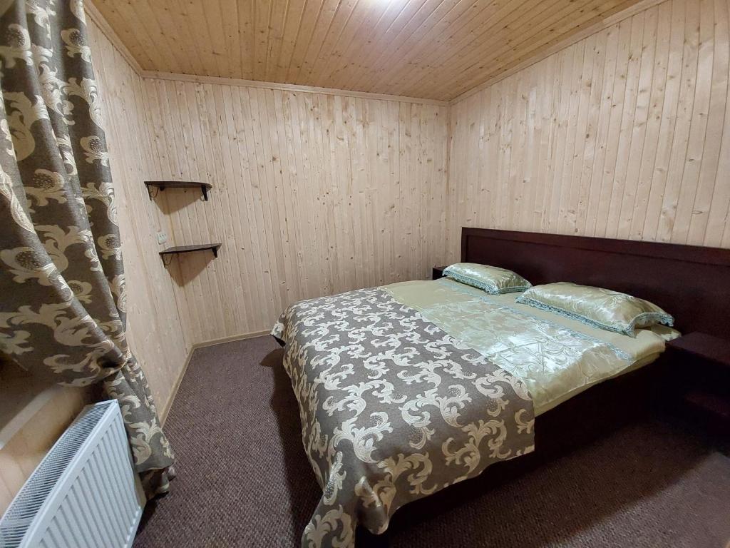 a bedroom with a bed in a room with wooden walls at Приватна садиба Два сини та донька in Bukovel