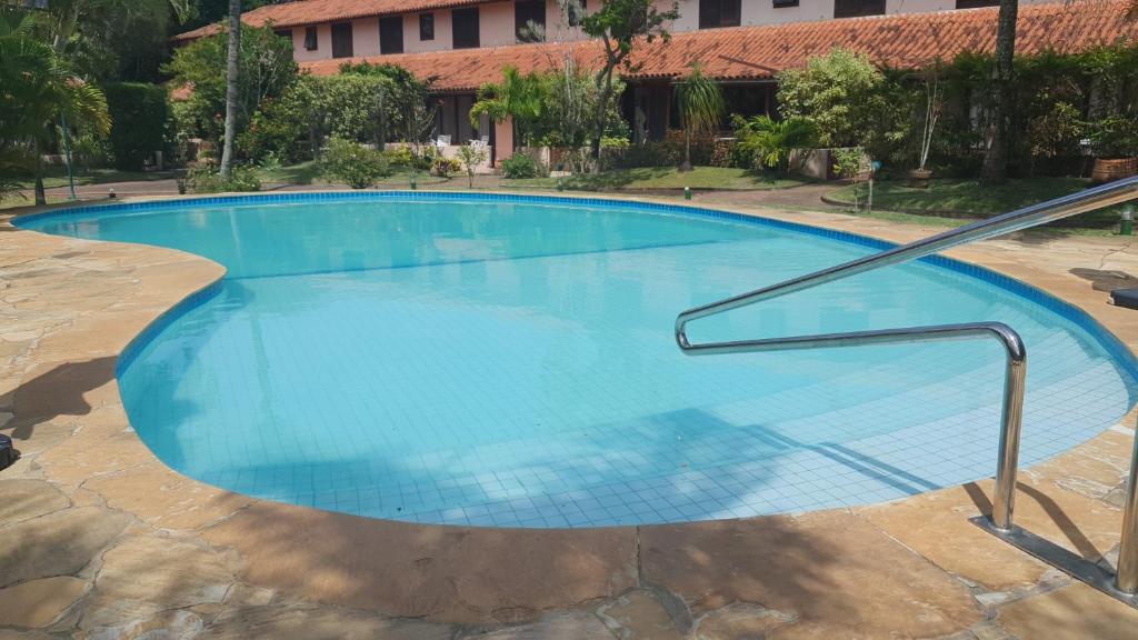 Casa 03 suites com ar. في بوزيوس: حمام سباحة أزرق كبير مع سكة حديد معدنية