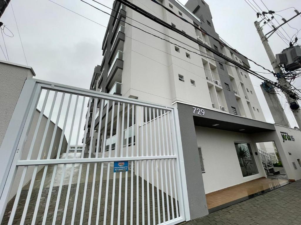 a white building with a gate in front of it at Apartamento Jardins Ubatuba in Ubatuba