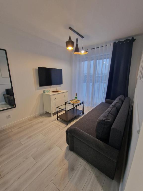 a living room with a couch and a flat screen tv at 68 - Apartamenty Siedlce - Nowy apartament w centrum przy ul. 3 Maja 51a in Siedlce