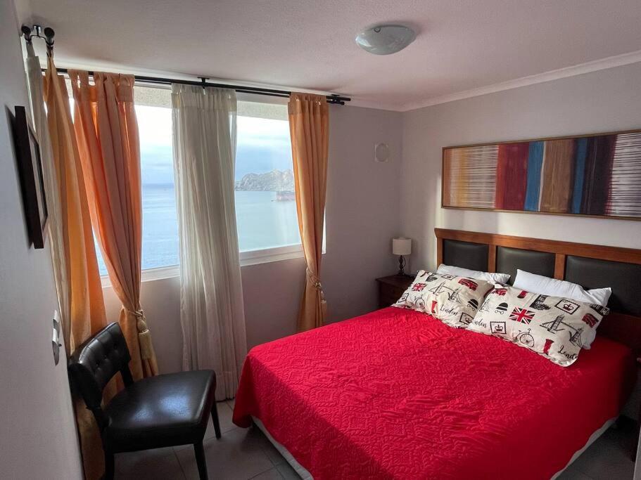 a bedroom with a red bed and a large window at Apartamento junto a la playa - Vistas Increíbles in Coquimbo