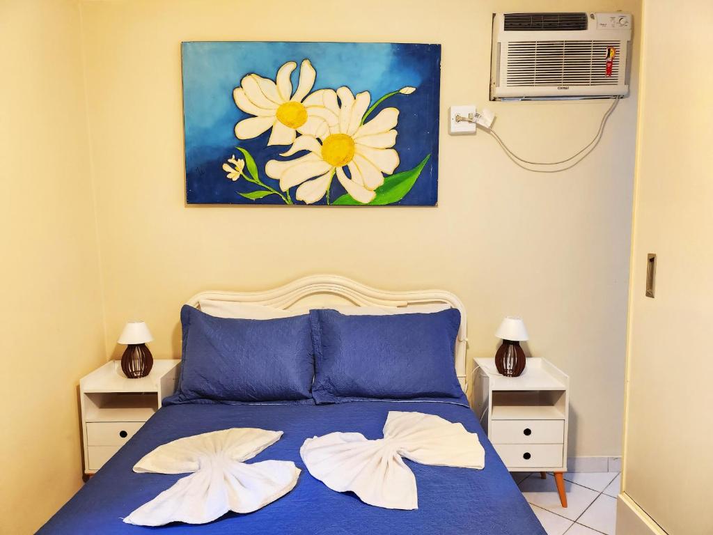 Un dormitorio con una cama azul con dos flores blancas. en Studio no Coração do Leblon JL311, en Río de Janeiro