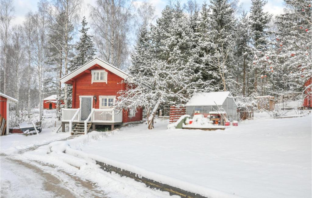 uma casa vermelha num quintal coberto de neve com árvores em Lovely Home In Gunnarskog With House A Panoramic View em Gunnarskog