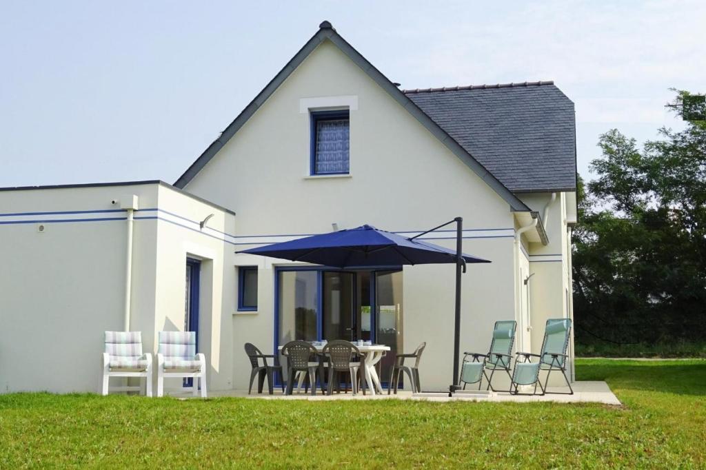 une maison blanche avec une table, des chaises et un parasol dans l'établissement Modern holiday home 500 m from the sea in Morgat, à Morgat