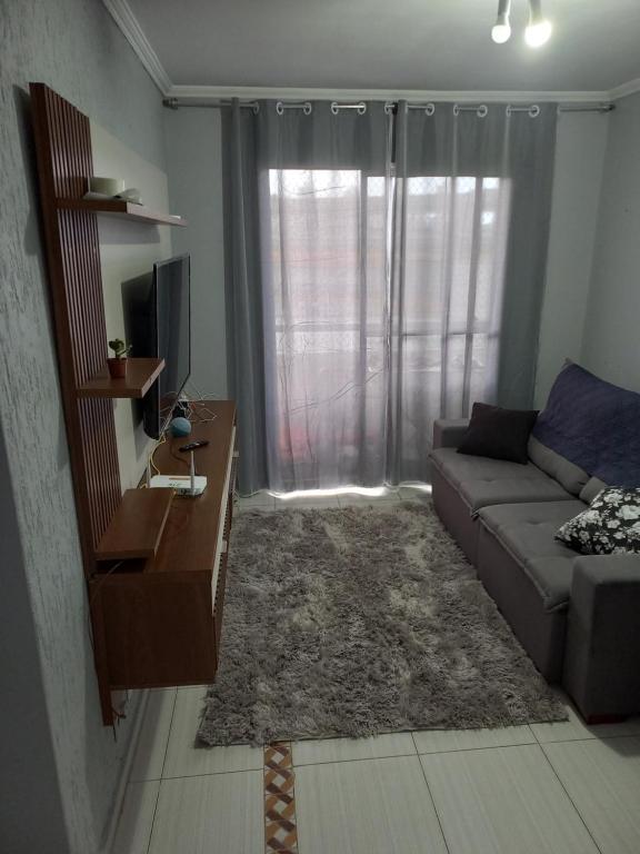 a living room with a couch and a television at Apto da Andreia in Praia Grande