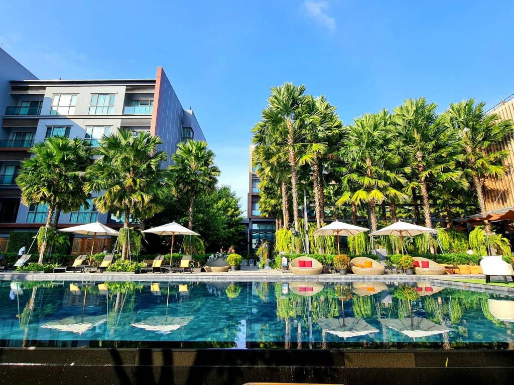 uma piscina em frente a um edifício com palmeiras em Aisana Hotel Korat em Nakhon Ratchasima