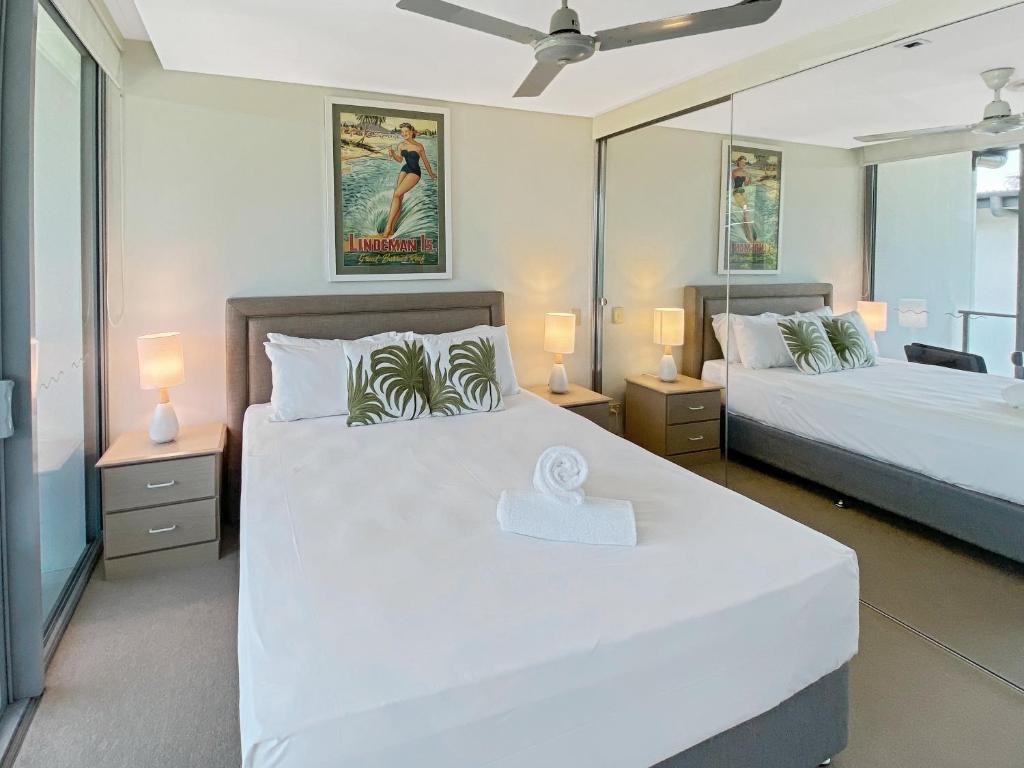a bedroom with two beds and a mirror at Serenity in Picnic Bay