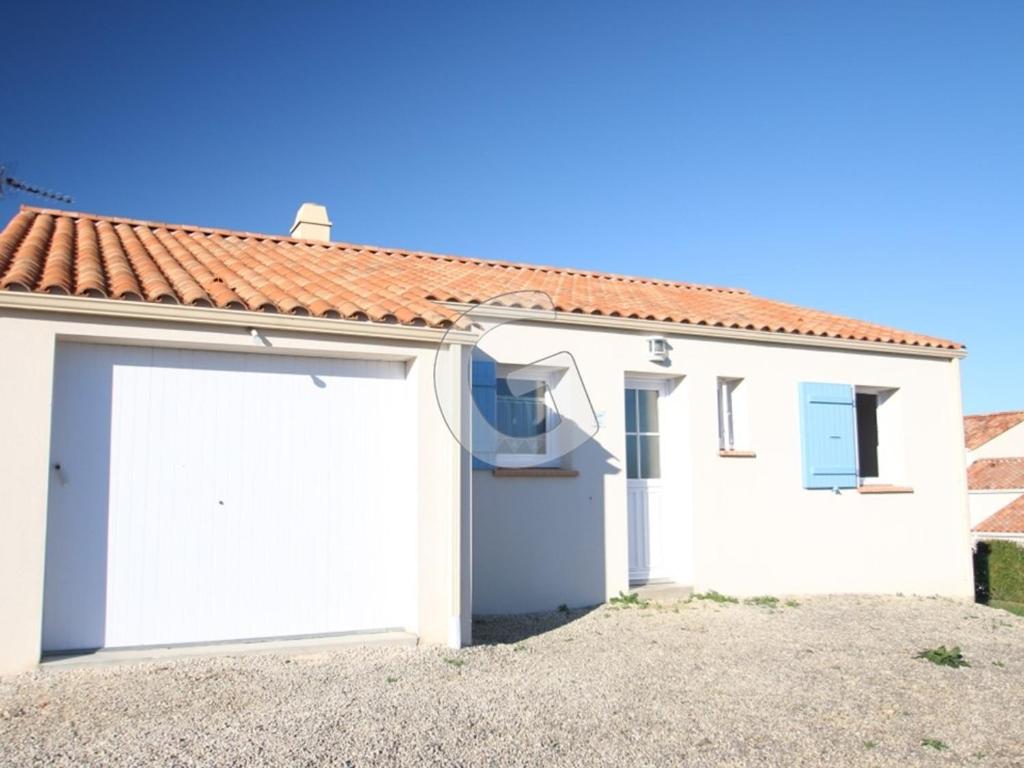 une maison blanche avec un garage dans l'établissement Charmante maison pour 4 personnes avec terrasse, à 1,8 km de la plage et proche des commodités - FR-1-357-76, à Saint-Vincent-sur-Jard