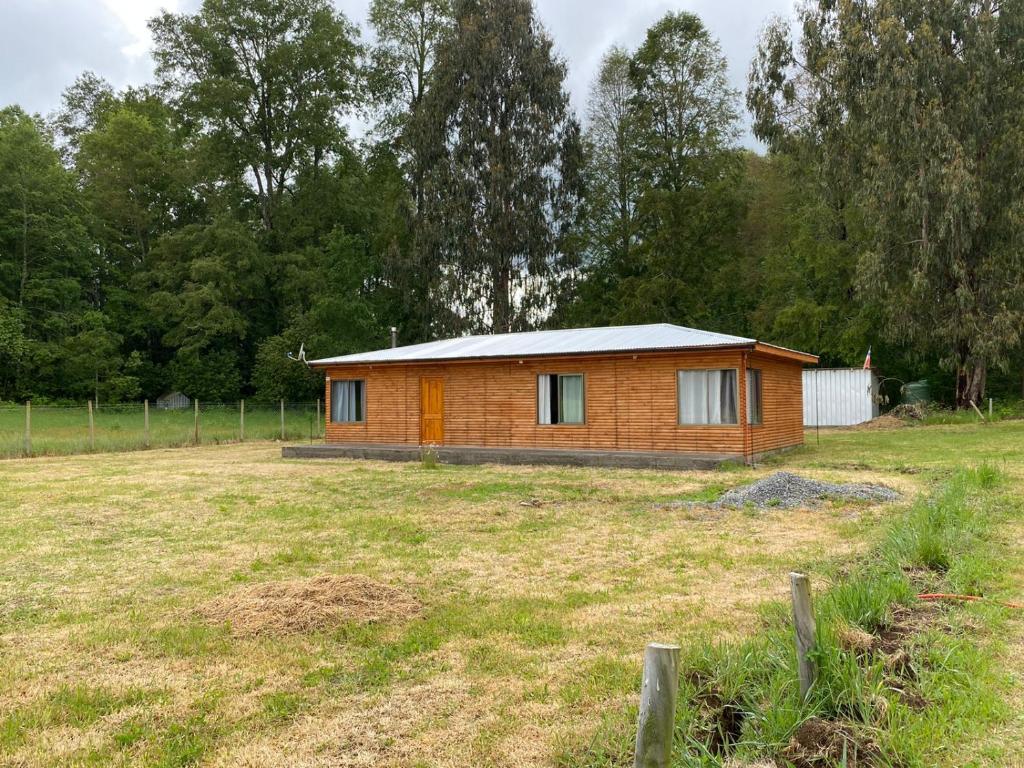 a small wooden house in a field with a yard at Cabaña Loncoche, villarrica in Loncoche