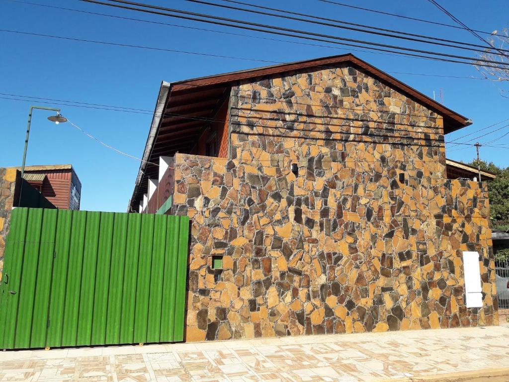 a building with a stone wall with a green door at Madre Selva Iguazu in Puerto Iguazú