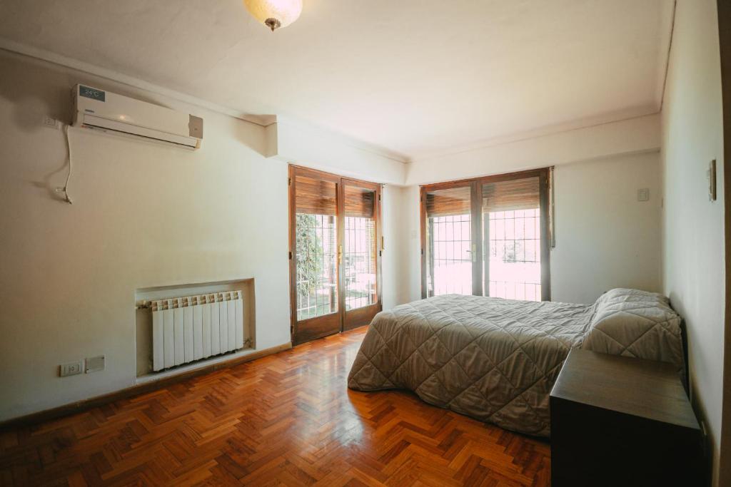 1 dormitorio con 1 cama, suelo de madera y ventanas en Casa Quinta Seccion en Mendoza