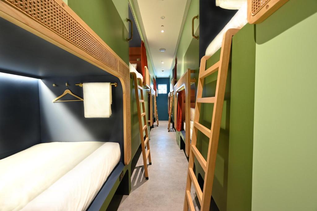 a room with two bunk beds and green walls at Dream Chaser Boutique Capsule Hotel in Singapore